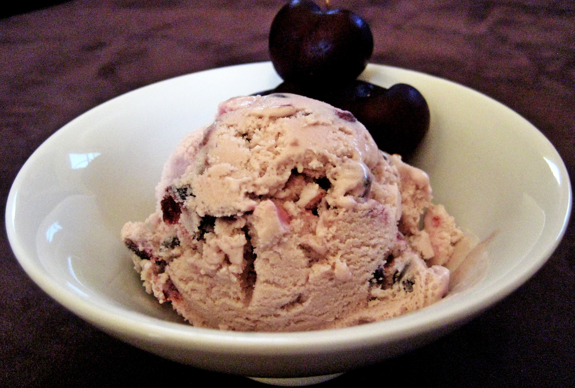 A delectable scoop of black cherry ice cream garnished with fresh cherries, set against a backdrop of vintage recipe cards and historical ice cream paraphernalia